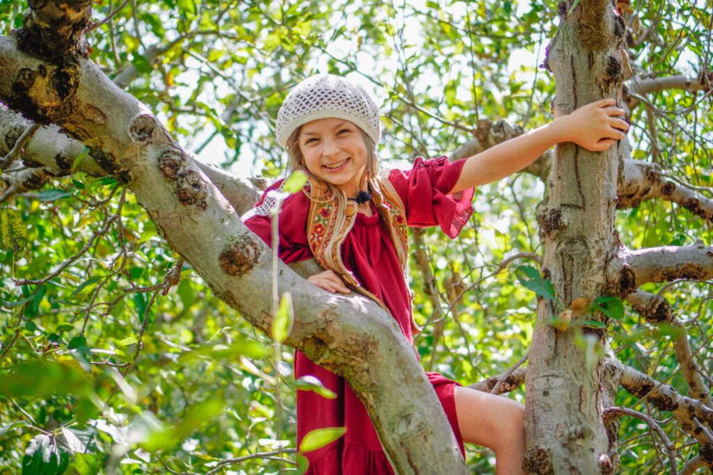 Young Girl pictured up in a tree resting on the tree limbs. Climbing trees is a time-honored childhood tradition and about as back-to-basics as summer fun gets. Go out on a limb and pretend you are still that monkey-kid you used to be and race your kids to the tippy top. 