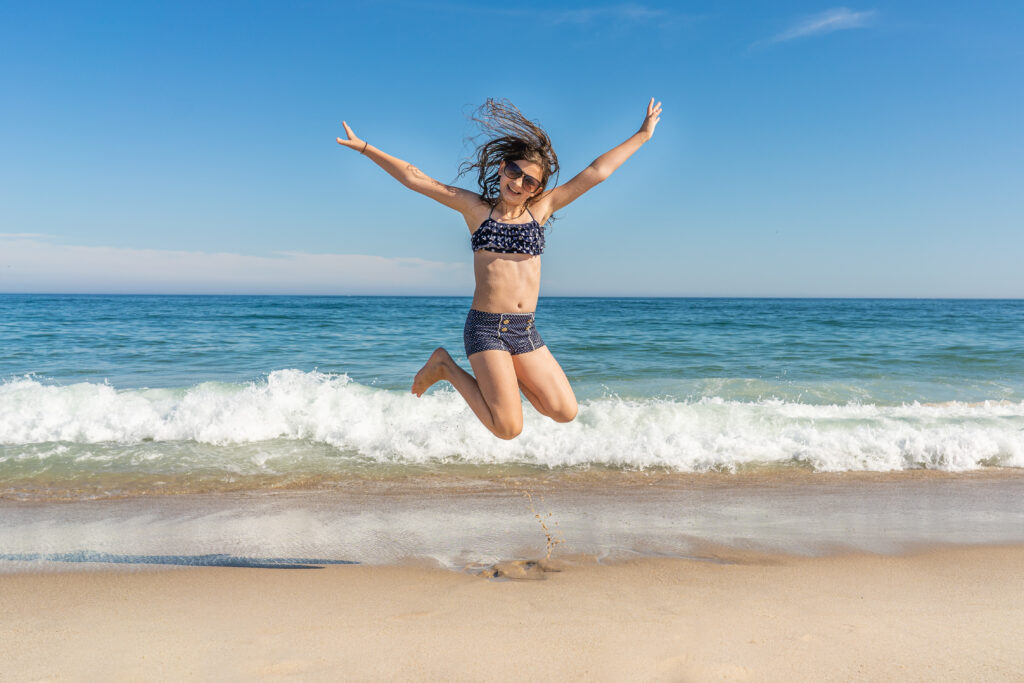 Girl on a secluded beach able to practice social distancing. If you can find a quiet corner where the sand meets the ocean it can be pure summer bliss. 