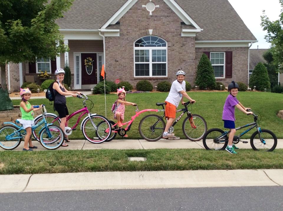 Family of five out on bike ride in neighborhood. Biking with the family in your neighborhood or local greenway can be a great safe option to get everyone moving.- Safe Summer Bucket List – 100 Ways to Have Fun This Summer While Social Distancing