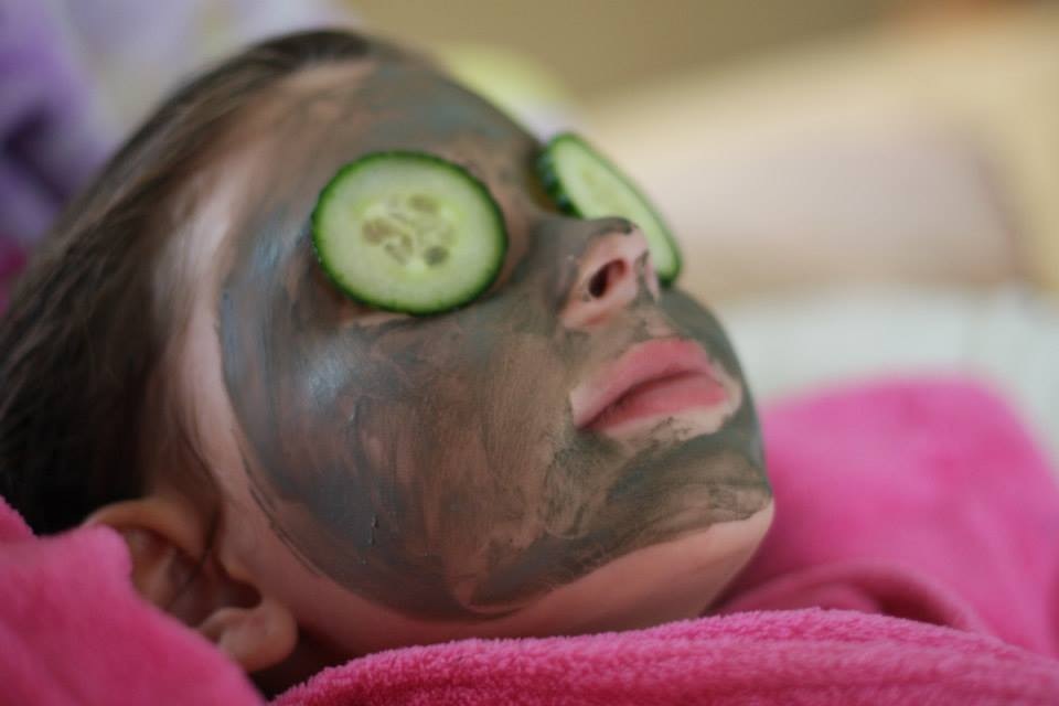 Young girl with cucumbers over her eyes and face mask relaxes during a "spa day". Get out the bath salts, nail polish and clay masks and enjoy a little spa time for everyone. You can take turns doing each other’s manicures and pedicures or just relax with some hot towels, cucumber eye pads, and candles. Whatever makes you feel pampered! 