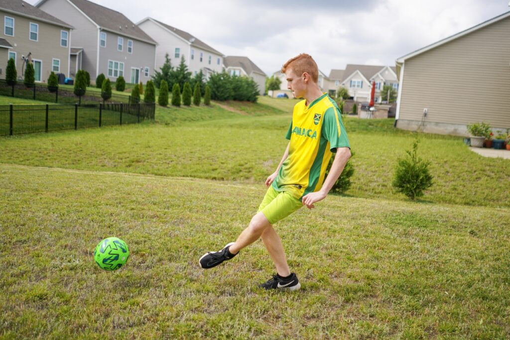 Boy kicks a soccer ball around in the back yard. Head outside with the kids to shoot some hoops, kick around the soccer ball or play some catch. We also love a good game of tennis or ping pong. 