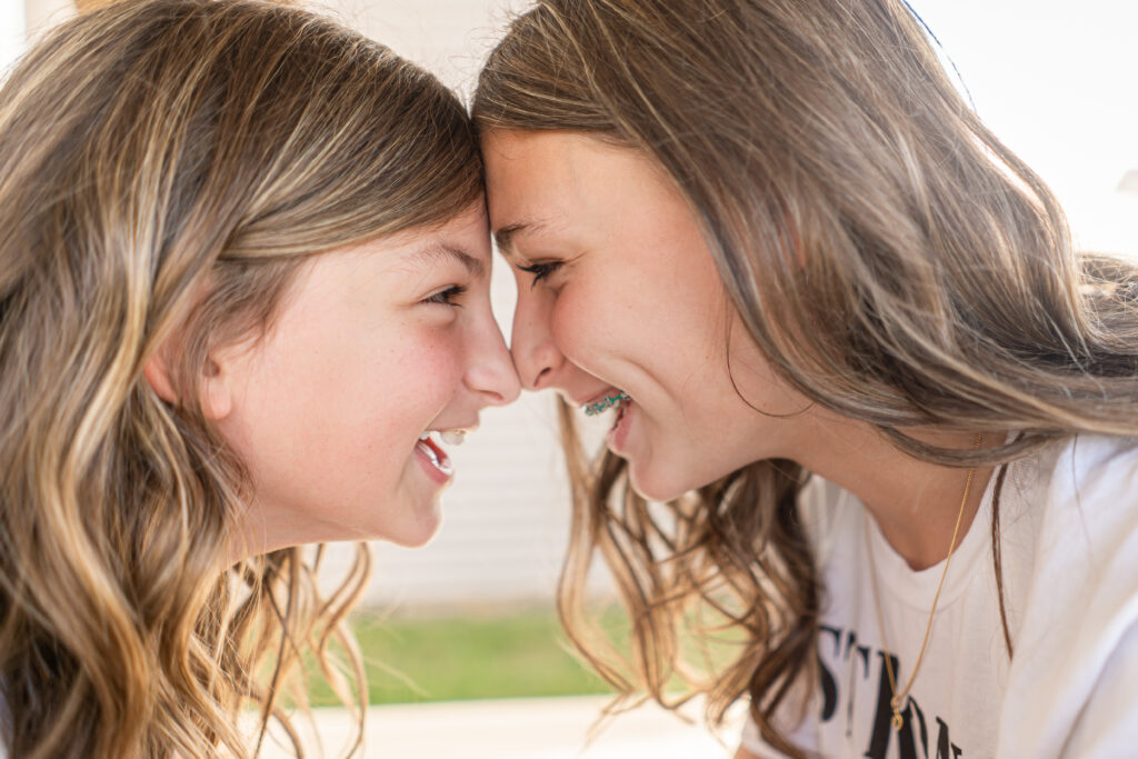 Sisters smiling at each other. - Safe Summer Bucket List – 100 Ways to Have Fun This Summer While Social Distancing