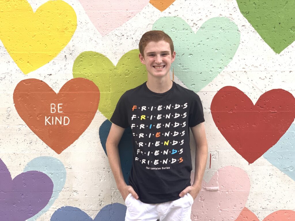 Teenage Boy stands in front of heart wall mural in Charlotte, NC. Art installations, sculptures and murals punctuate many urban landscapes. Take a leisurely stroll or hop on two wheels and explore the public art in your area. Snap some selfies for social media of your findings. 