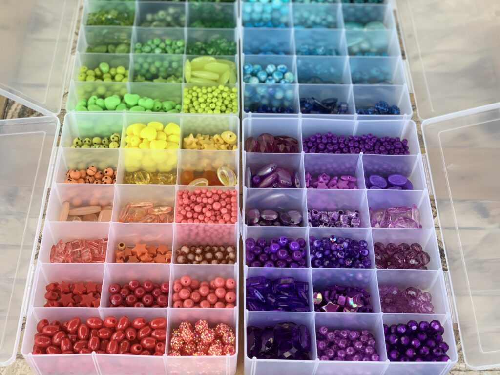 Bins filled with colorful beads. A jewelry craft encourages creative expression and leaves you with a fun finished product of your design. - Safe Summer Bucket List – 100 Ways to Have Fun This Summer While Social Distancing