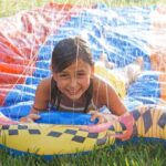 Girl smiles happily on colorful slip and slide.