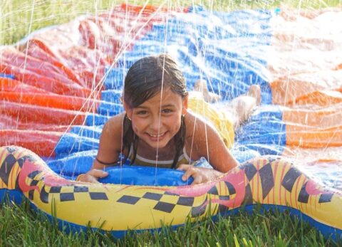 Girl smiles happily on colorful slip and slide.