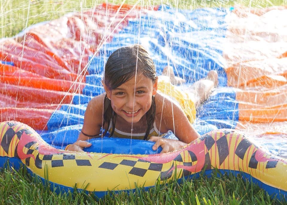 Girl smiles happily on colorful slip and slide.