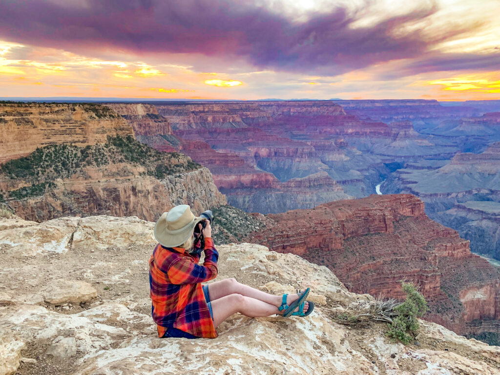 Woman looks out at sunset over Grand Canyon from Hopi Point. Virtually touring a national park is a fun way to pass the time and scout places for a future in-person exploration.