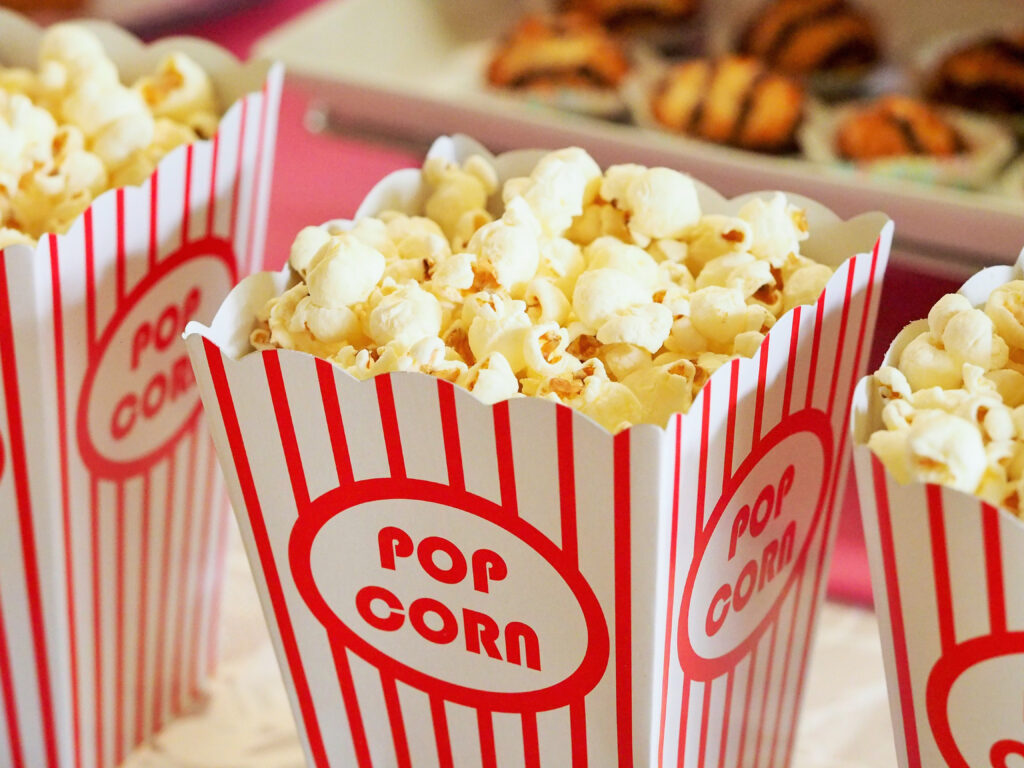 Photo of Pop Corn in buckets for a Family Movie NIght. Cuddle up on the couch with some popcorn and candy and enjoy a classic or check out something new on one of the streaming platforms like Netflix, Hulu, Amazon Prime Video, or Disney+. Change things up by watching along with friends using the Netflix Party feature on Netflix online or take your movie night outside with a projector and screen. - Safe Summer Bucket List – 100 Ways to Have Fun This Summer While Social Distancing