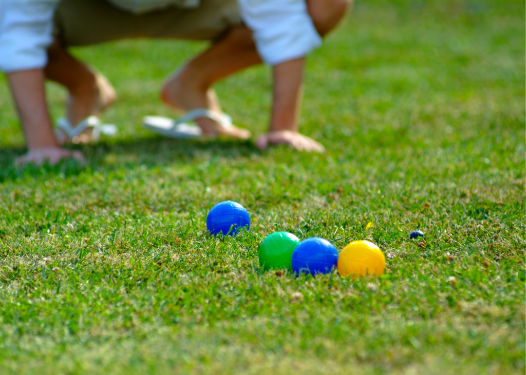 Clue-up photo of a game of Bocce Ball being played on a lawn. Invest in a croquet set, bocce ball set up, or badminton kit. Even an inexpensive frisbee can keep your family entertained for hours. 