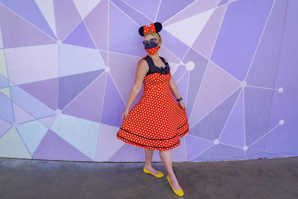 Woman poses in front of the Purple Wall in the Magic Kingdom at Disney World. An adult's only Disney World vacation allows you to focus on you!